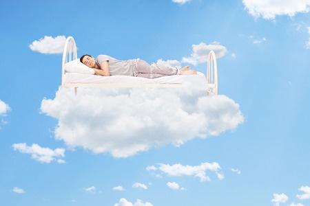37120773 - man sleeping on a bed in the clouds high up in the sky